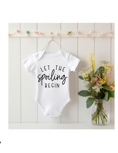 Introduce your little one to the world of love and affection with our adorable baby bodysuit, specially crafted for those cherished moments with grandparents. Made from 100% soft, breathable cotton, this pristine white bodysuit ensures ultimate comfort for your baby's delicate skin. Emblazoned with the playful phrase "Let the Spoiling Begin" in sleek black heat transfer vinyl, this bodysuit is a delightful reminder of the joy and pampering that grandparents bring. The durable vinyl design stands White Cotton Onesie As A Gift, Fitted White Short Sleeve Bodysuit With Letter Print, White Onesie With Letter Print For Gender Reveal, Fitted White Onesie For Baptism, White Fitted Onesie For Baptism, Fitted Cotton Bodysuit For Baptism, White Cotton Bodysuit Gift, Personalized White Bodysuit For Gift, White Short Sleeve Onesie For Baptism