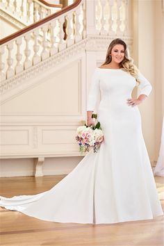 a woman in a white wedding dress standing next to a stair case with flowers on it