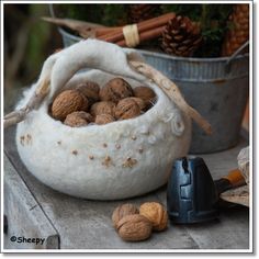 some nuts are in a white basket on a table next to a shovel and pine cones