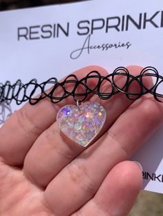 Each resin pendant is handmade to order, therefore no two chokers are identical! However, I try to get as close to the listing photos as possible :) One size fits all black elastic tattoo choker necklace. Made with clear epoxy resin and white chunky holographic glitter ✨ Heart width is approximately 19mm Thanks for visiting my shop! 🌈 Adjustable Black Rave Choker, Adjustable Black Rave Style Choker, Adjustable Rave Choker As Gift, Adjustable Rave Choker For Gift, Adjustable Rave Choker For Gifts, Trendy Black Heart-shaped Choker, Trendy Black Heart Choker, Black Rave Style Choker Jewelry, Cute Adjustable Black Choker