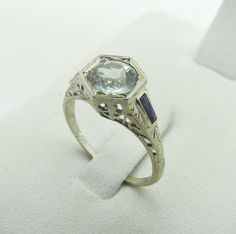 This listing is for a gorgeous solid 18k White Gold Genuine Aquamarine & Sapphire Ring. ​Very unique Antique Filigree design This ring really stands out and is a sure conversation piece! Features a 1.00 carat Aquamarine center stone and blue sapphire accent stones on the sides as pictured. ​​​​​Ring measures size 6 1/2 with a nice weight of 2.6 grams. ​Top side Measures aprox. 9 mm tall. Ring has been completely checked & tested & verified by our pro staff and is in very good vintage condition as pictured. Pics are of the actual ring you will receive! California residents will be charged sales tax @ 10% Ring will be shipped fully insured! stock # 1286 18k White Gold ANTIQUE ART DECO FILIGREE Aquamarine & Sapphire RING Vintage 6.5 18k White Gold ANTIQUE ART DECO FILIGREE Aquamarine & Sapphi Sapphire Ring Vintage, Vintage Sapphire Ring, Art Deco Filigree, Antique Jewelry Rings, Antique Filigree, Filigree Design, Unique Antiques, Antique Art Deco, Ring Vintage