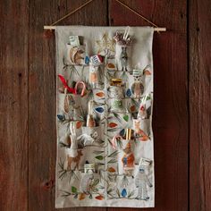 a tea towel hanging on a wooden wall with an assortment of items attached to it