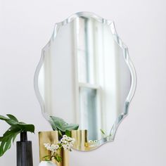 a mirror sitting on top of a table next to a vase