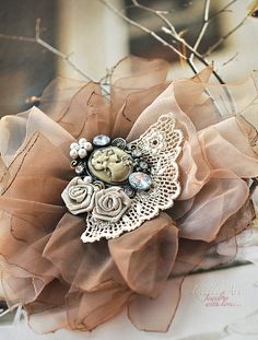 a close up of a brooch on a piece of cloth with lace and flowers