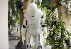 a robot is standing in front of some flowers