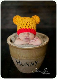 a baby is wearing a crocheted winnie the pooh hat while laying in a pot