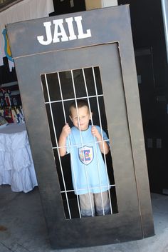 a young boy standing behind bars in a jail cell