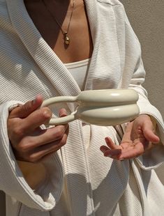 a woman wearing a white robe and holding an object in her hands with both hands