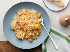 a blue plate topped with rice and ham next to a wooden spoon on top of a table