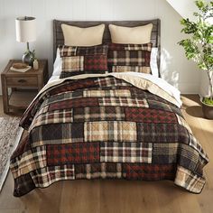 a bed with a plaid comforter and pillows on top of it in a room