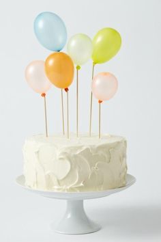 a white cake topped with lots of balloons