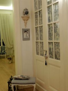 an entry way with a bench and clock on the wall next to two doors that have glass panes above them