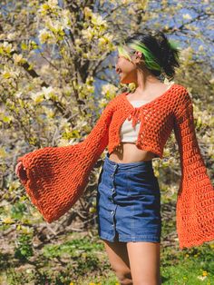 a woman with green hair wearing an orange knitted sweater and denim miniskirt