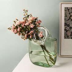 a glass vase with flowers in it on a table next to a framed photo and an empty frame