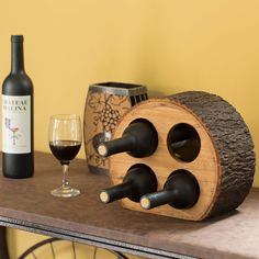 a wooden wine rack with bottles and glasses on a table next to a glass of wine