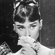 a woman eating food while wearing a tiara and holding a mirror in front of her face