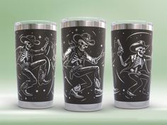 three stainless steel tumblers with skeletons and stars on them, one is holding a guitar