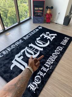 a man pointing at a sign that says rock and roll on the floor in front of a window