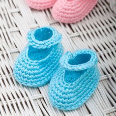 two crocheted baby shoes sitting on top of a wicker table