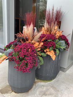 two planters with flowers in them sitting on the ground