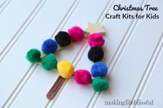 a christmas tree craft for kids with pom - poms and a wooden stick