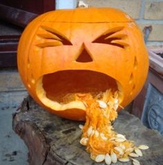 a carved pumpkin with its mouth open and sunflower seeds coming out of it's side