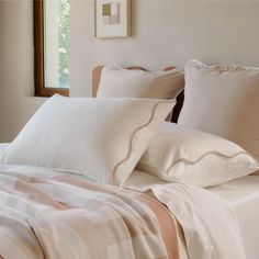 a bed with white sheets and pillows on it