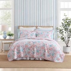 a bed in a room with blue and pink wallpaper on the walls next to a window