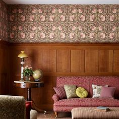 a living room with wood paneling and pink couches in front of a wooden wall