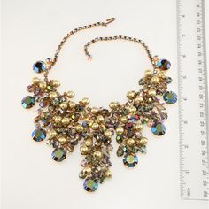 This is part of Chairish’s Costume Jewelry assortment.  Juliana (made by DeLizza & Elster) bib necklace comprised of smoky navette and aurora borealis iridescent rhinestones topped with dangling beads in smoky iridescent and textured gold colors. Setting is gold plated. Unmarked, since only select DeLizza & Elster items were marked with Juliana hang tags. Measures right at 16 inches long; front drop is about 3 inches in the front. Condition is excellent with no missing stones and beautiful gold Rhinestone Top, Gold Colors, Bib Necklace, Gold Texture, Beaded Dangles, Beads Necklace, Hang Tags, Aurora Borealis, Costume Jewelry