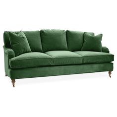 a green velvet couch with four pillows on it's arms and legs, against a white background