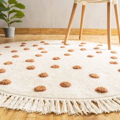 a white rug with brown polka dots on it in front of a chair and potted plant