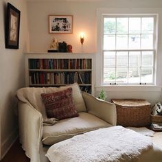 a living room filled with furniture and bookshelves next to a window in front of a book shelf