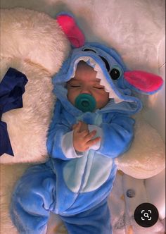 a baby in a blue costume laying next to a stuffed animal