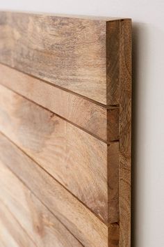 a close up of a wooden headboard on a wall with white walls in the background