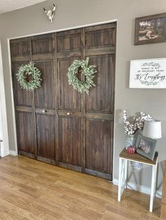 two wreaths are hanging on the wooden doors in this entryway to a home