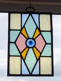 a stained glass window with a blue eye in the center and sky behind it on a cloudy day