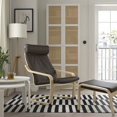 a living room with a chair, ottoman and rug on the floor in front of a door