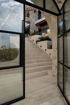 an open door leading up to a set of stairs in front of a building with large windows