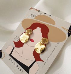 a close up of a pair of earrings on a card with an image of a woman's face