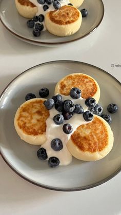 two plates with pancakes and blueberries on them