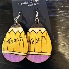 a pair of wooden earrings with the words teach written on them