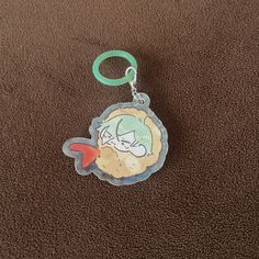 a keychain with a cartoon character on it sitting on a brown carpeted surface