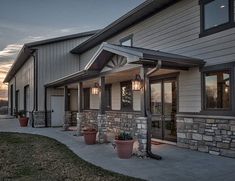 the front of a house that is lit up at night with lights on and potted plants outside