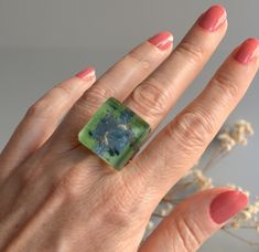 a woman's hand wearing a ring with a painting on it