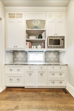 a kitchen with white cabinets and silver counter tops