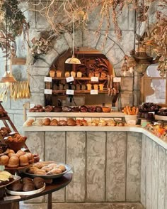 an assortment of breads and pastries on display in a bakery with stone walls