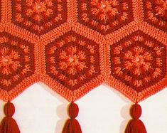 three crocheted tassels are hanging on the wall with red tassels