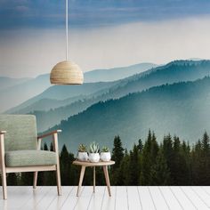 a chair and table in front of a wall with a mountain scene painted on it