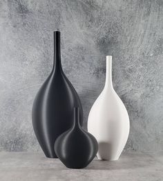 two black and white vases sitting next to each other on a gray table top